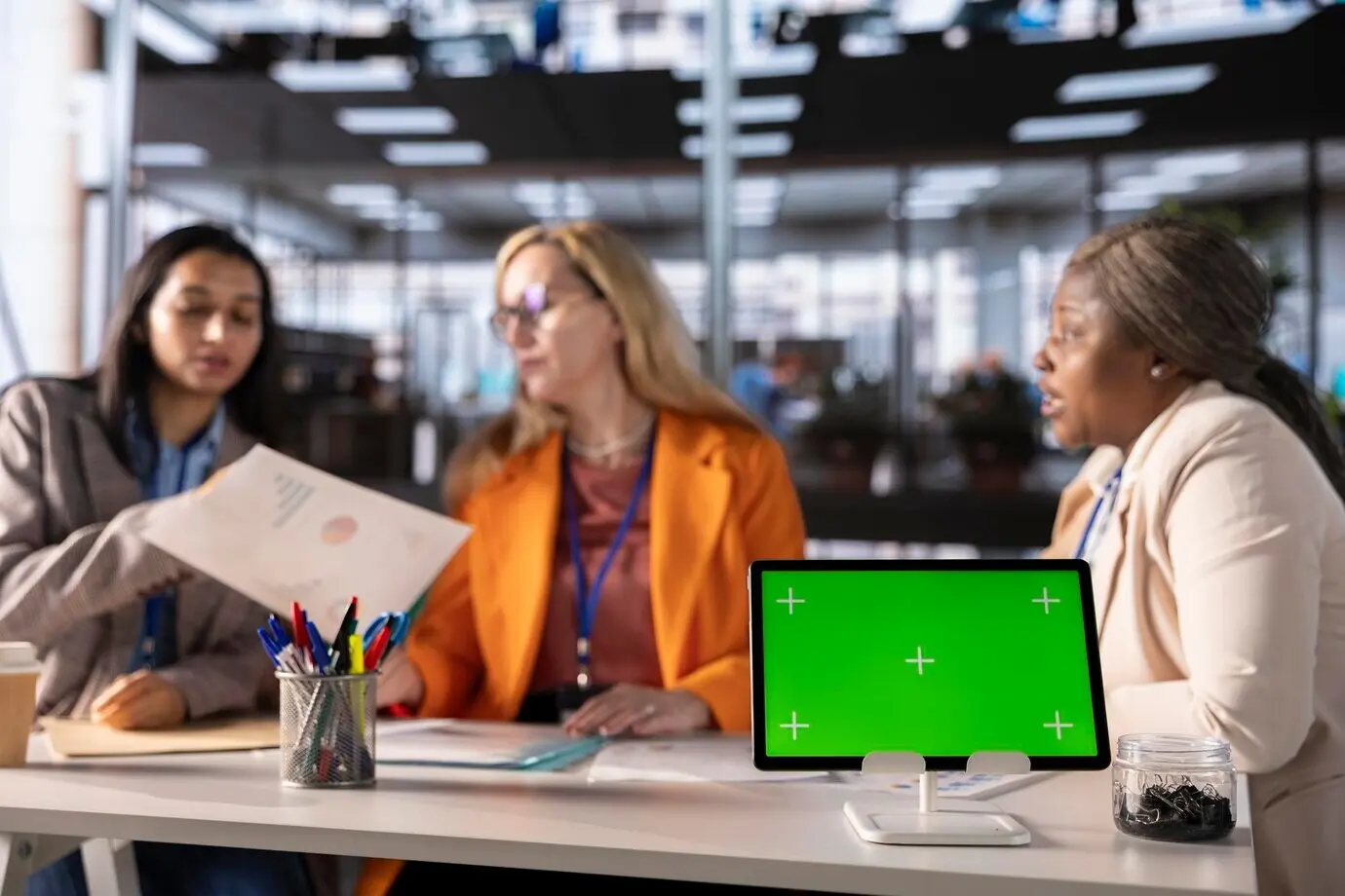Бизнесвумен из разных этнических групп работают рядом с изолированным зелёным экраном.